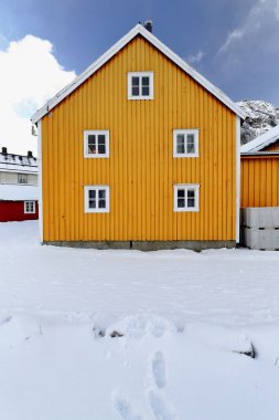 Old wooden port warehouse painted yellow-closed casement windows with white wooden windowframes-storehouse on the gangplank-pier on the N.side of the fishing port. Nusfjord-Flakstadoya-Lofoten-Norway.