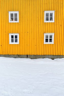 Old wooden port warehouse painted yellow-closed casement windows with white wooden windowframes-storehouse on the gangplank-pier on the N.side of the fishing port. Nusfjord-Flakstadoya-Lofoten-Norway.