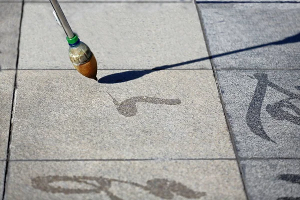 中国书法在城市中央广场的地砖上 是用一根长棍尖插着的大刷子喷出的水珠画出来的 张业甘肃省 — 图库照片
