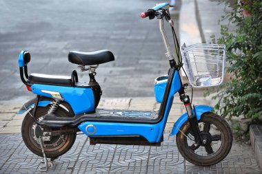 Bir lokantanın önünde park etmiş yalnız mavi elektrikli scooter sahibinin öğle yemeğini bitirip restoranı terk etmesini bekliyor. Ming ve Qing hanedanlarının restore edildiği antik yemek caddesinde. Zhangye-Gansu-Çin.