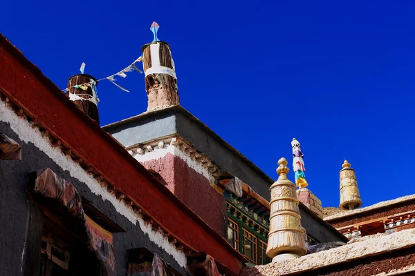 Латунь и ткань дхвахас-победные знамена на красно-серых зданиях. Сакья-Тибет. 1843 год — стоковое фото