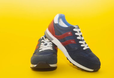 Sarı arka planda izole edilmiş modern mavi erkek spor ayakkabılarına yakından bakın..