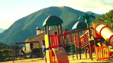 Çocuklar dağların arka planında oyun oynuyorlar.