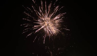 Turuncu, siyah gökyüzü arka planında bulanık havai fişek ışıkları. Yeni yıl ve Noel kavramı.