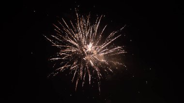 Turuncu, siyah gökyüzü arka planında bulanık havai fişek ışıkları. Yeni yıl ve Noel kavramı.