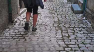 Arkadan ateş ediyorlar. Kadın caddede yürüyor. Dönüyor ve gülümsüyor. Kamera, sırt çantalı genç bir turisti izliyor.
