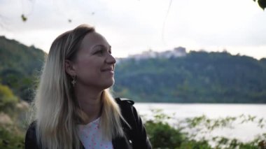 Parkta tek başına duran, gülümseyen ve kameraya bakan genç bir kadının yakın plan portresi. İnsanlar ve tarz kavramı