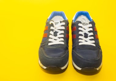 Sarı arka planda izole edilmiş mavi spor ayakkabılar..