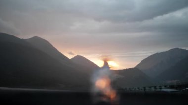 the sun sets over the mountains, the sunset in the foreground is a defocused fountain