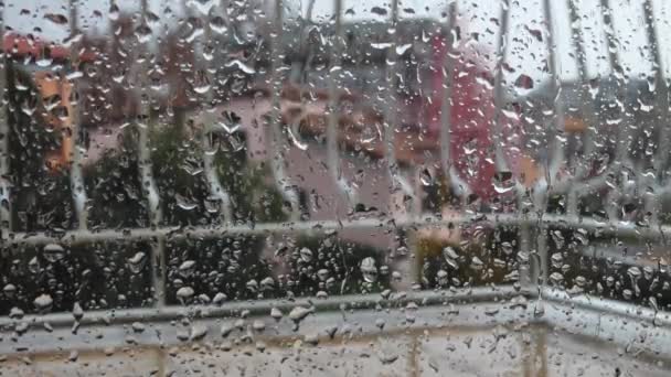 Vista cercana de las gotas de agua que caen sobre el vidrio. Está lloviendo por la ventana. Temporada de lluvias, otoño. Gotas de lluvia fluyen abajo — Vídeo de stock