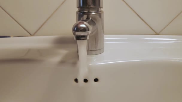 De kraan wordt geopend, het water stroomt in het afvoerbassin, daarna werd gesloten. Giet water, barst in de kraan — Stockvideo