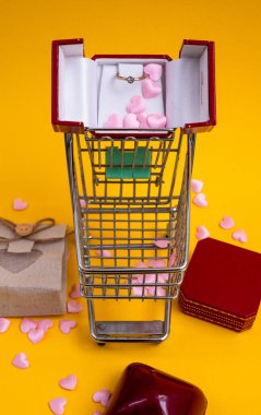 Kamyonetin içinde kırmızı kalpler var. Kırmızı kalplerle dolu küçük bir araba ve hediye çantası. Sevgililer günü için tebrik kartı, tatil, düğün ya da doğum günü sarı arka planda