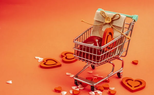 Corazones rojos dentro del camión. Mini-carrito lleno de corazones rojos y una bolsa de regalo. Tarjeta de felicitación para San Valentín, día festivo, boda o cumpleaños sobre un fondo rosa — Foto de Stock