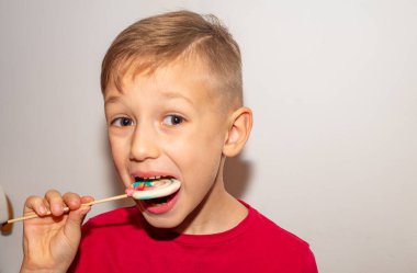 Bir çocuk çubuğun üzerinde çok renkli bir şeker yer. Elinde şeker lolipopu olan bir çocuk.