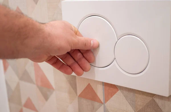 Man trycker på en knapp på avloppstanken i badrummet — Stockfoto
