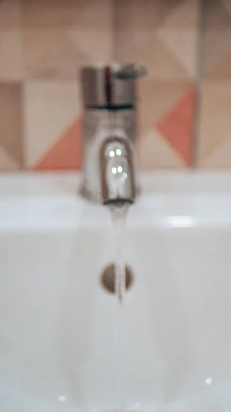 Water flows from a metal tap. Close up, defocus — Stock Photo, Image