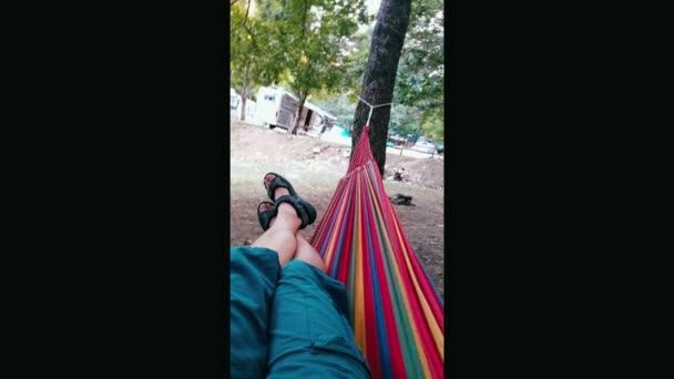 Ноги молодого человека, лежащего на гамаке размахивая — стоковое видео