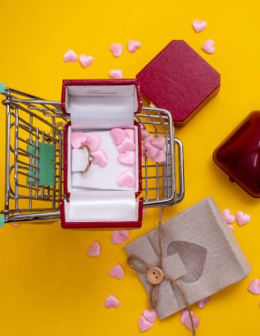 Kamyonetin içinde kırmızı kalpler var. Kırmızı kalplerle dolu küçük bir araba ve hediye çantası. Sevgililer günü için tebrik kartı, tatil, düğün ya da doğum günü sarı arka planda