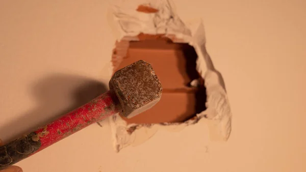 Costruttore fa un buco nel muro con un martello, da vicino — Foto Stock