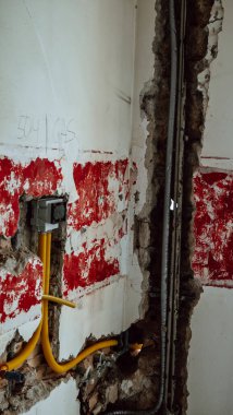 Duvardaki kapıya yeni borular döşemek, su ve gaz tesisatı tamiri. İnşaat ve onarım sırasında tuğla duvardaki su boruları.