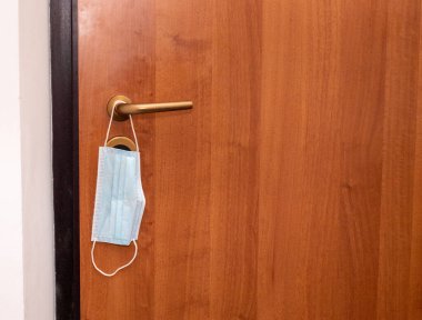 Kapı kolunda asılı bir yüz maskesi. Coronavirus COVID19 'u maskeliyor. Antivirüs maskeleri