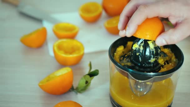 Homem mãos juicing fruta laranja fresca no juicer 4k câmera lenta close-up vídeo. Preparação de suco cítrico beber em casa cozinha. Espremendo no espremedor. Dispositivo de extracção eléctrica utilizado para separar healt — Vídeo de Stock