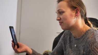 Video konferans üzerinden annesiyle konuşmak için akıllı telefonu kullanan genç bir kız.