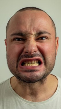 Beyaz arka planda izole bir şekilde kameranın önünde dilini dışarı çıkaran komik, öfkeli genç bir zorbanın yakın plan portresi. İğrenç bir kavramsın.