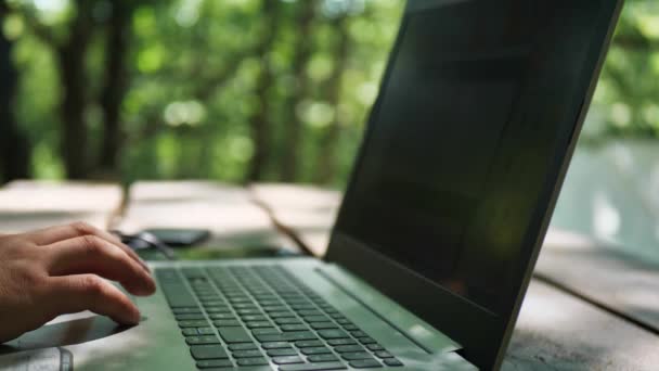 Sms on the phone while working on a laptop. man working on laptop in nature — Stock Video