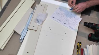 Adam talimatlara göre evde ahşap bir çekmece kuruyor.