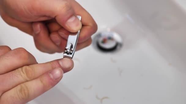 Egy fiatalember vágja a körmeit a mosogató fölött a Clippers. Közeli kezek — Stock videók