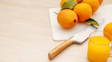 Sıkıştırılmış portakal suyu ve taze portakal meyveleri ahşap masada..