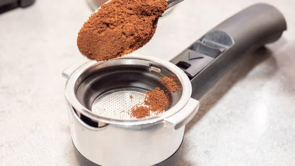 person makes coffee in a coffee machine picks up ground coffee with a spoon from a coffee grinder drawer