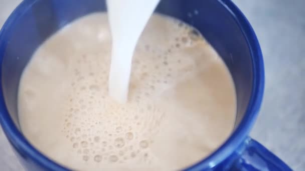 Lägga mjölk till en blå kopp på bordet. Mjölkkaffe. Långsamma rörelser — Stockvideo