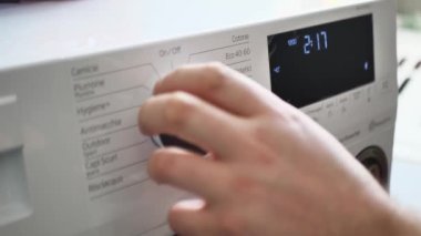 Adam düğmenin üstündeki çamaşır makinesini açar. Kapat.