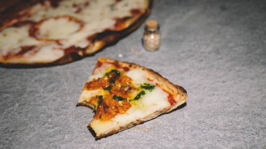 Gri arka planda bir dilim baharatlı pizza..