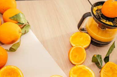 Taze portakal suyu döküyorum. Tahtaya sıkıştırılmış portakal parçaları. Taze portakal suyu bardağını kapat. Sağlıklı ve vejetaryen diyeti, mutfak masasında meyve suyu.