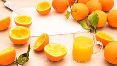 Taze portakal suyu döküyorum. Tahtaya sıkıştırılmış portakal parçaları. Taze portakal suyu bardağını kapat. Sağlıklı ve vejetaryen diyeti, mutfak masasında meyve suyu.