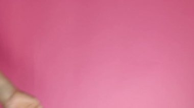dikey video. El hareketleriyle. Bir el merhaba. Pembe arka planda izole edilmiş. Reklam kavramı.