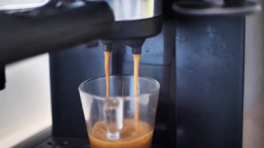 Kahve makinesinin fincanından dökülen kahvenin görüntüsü. Ev yapımı sıcak Espresso. Filtre tutacağı kullanılıyor. Taze kahve akıyor. Sabahları kavrulmuş sade kahve içmek..