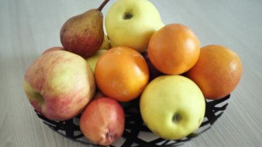 Elmalar ve portakallar masada bir kasede.