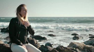 Su yüzeyinin üstündeki deniz taşlarında oturuyordu.