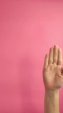 dikey video. El hareketleriyle. Bir el merhaba. Pembe arka planda izole edilmiş. Reklam kavramı.