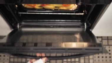 Kadın fırından sebzeli balık çıkarıyor.