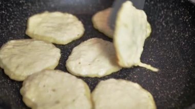 Bir adam kızartma tavasında Draniki 'yi döndürür.