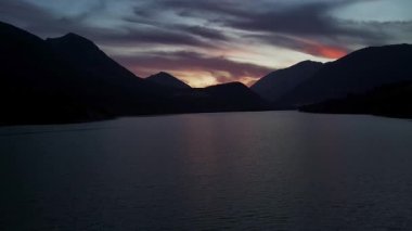 İnsansız hava aracı gün batımında gölün üzerinde uçuyor.