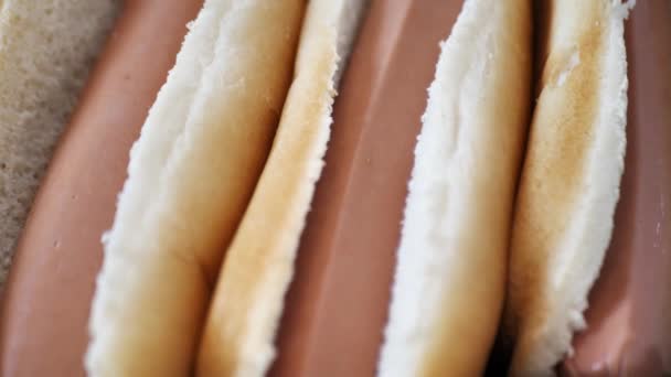 Worsten in gesneden broodjes. losse flodders voor hotdog. close-up — Stockvideo