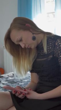 dikey video. Kadın telefona bakar ve gülümser.