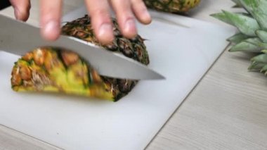 Kesme tahtasıyla ananas kesen bir adamın ellerinde.