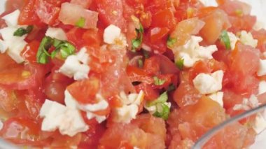 Bir kaşık fesleğenli domates salatası ve mozzarella karışımı.